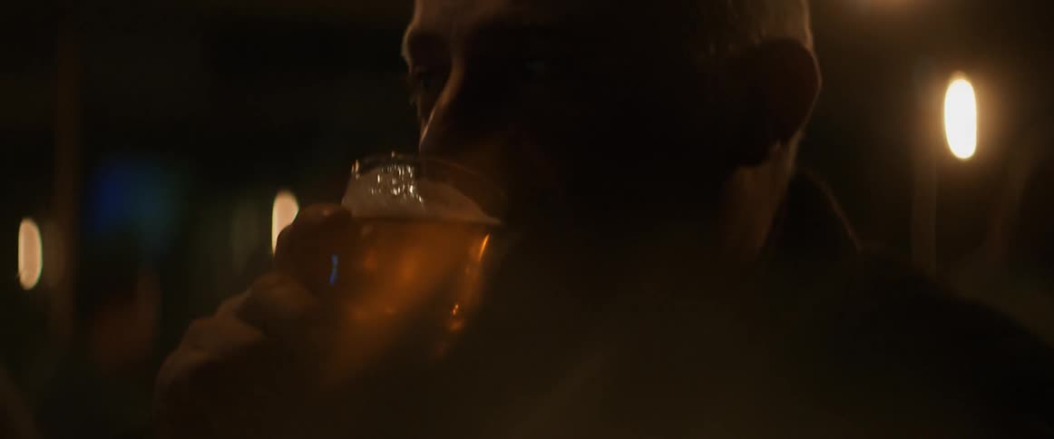 A man drinking a beer inside with lights in the background