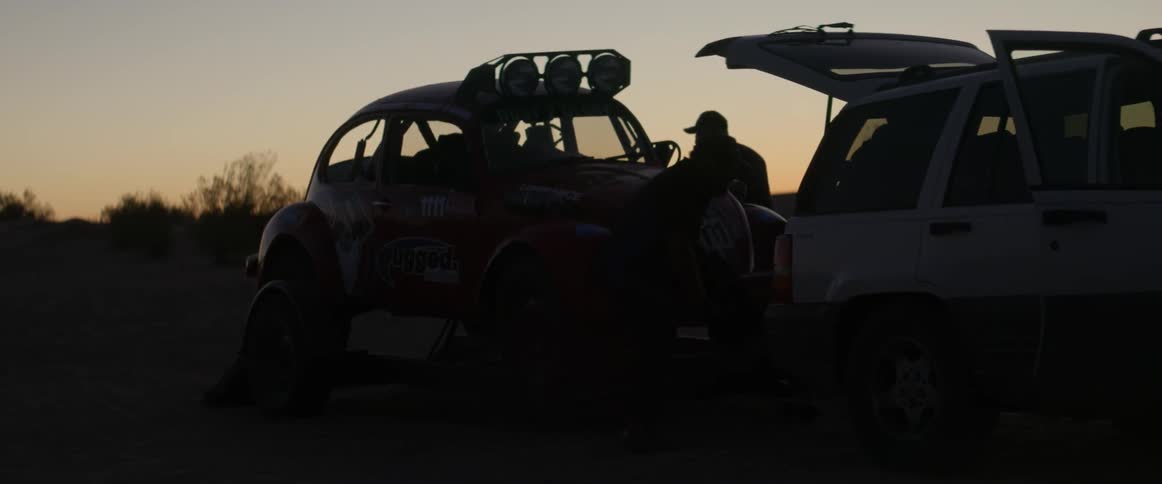 A man works on a rally car at dusk