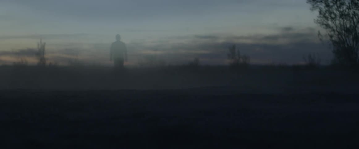 A man walks outside at dusk