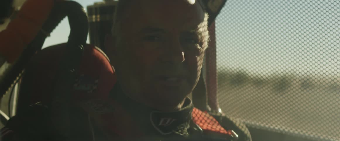 A man removes a rally car helmet in frustration