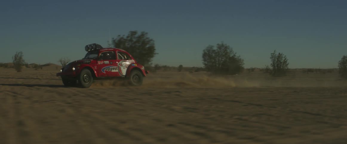 A man drives a rally car through the desert