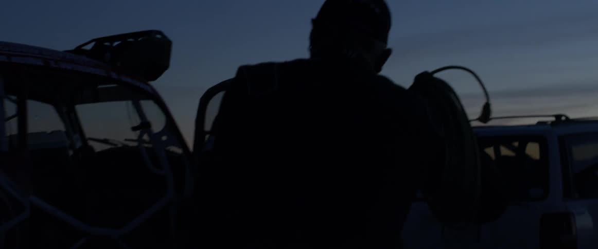 A man walks over to a car at dawn