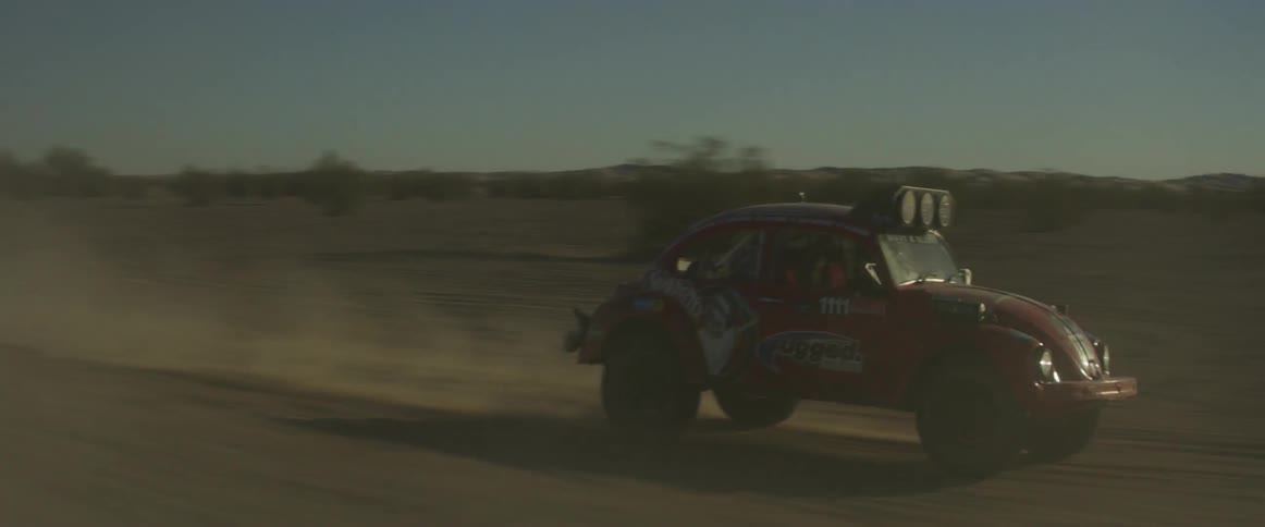 A man drives a rally car through the desert