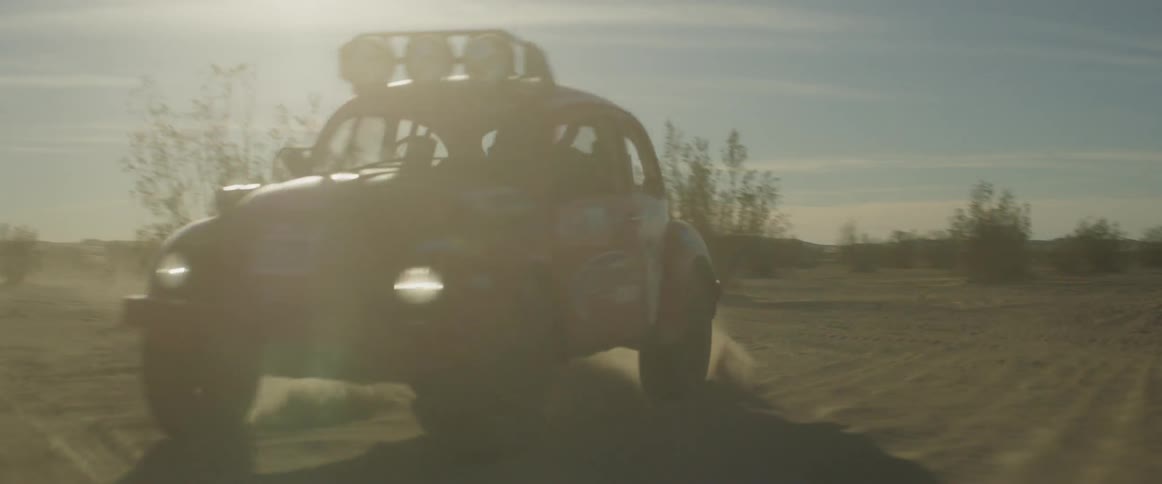 A man drives a rally car through the desert