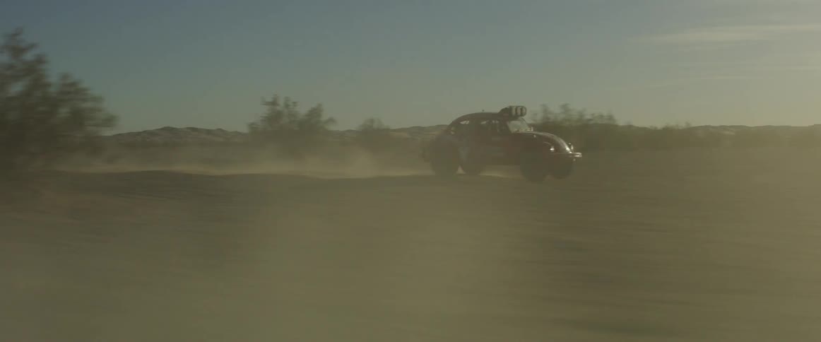 A car jumps over small hills in the desert