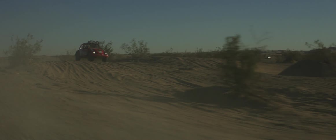 An off-road racing vehicle drives across the desert