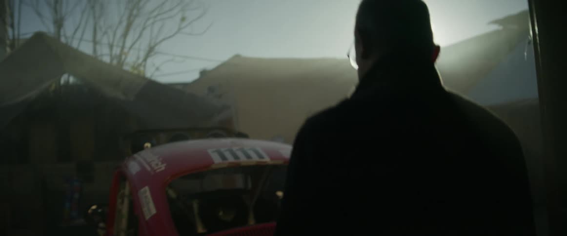 Older man looking at his car once he leaves an old building at sunset