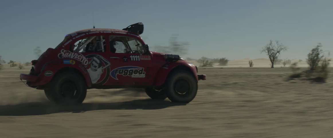 A man drives a rally car through the desert