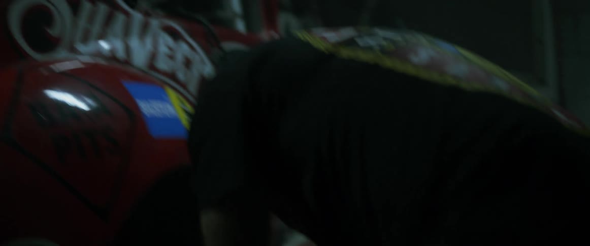 A man changes a tire in a dim garage