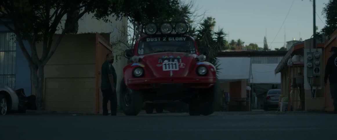 Red vehicle turns a corner and travels down the road