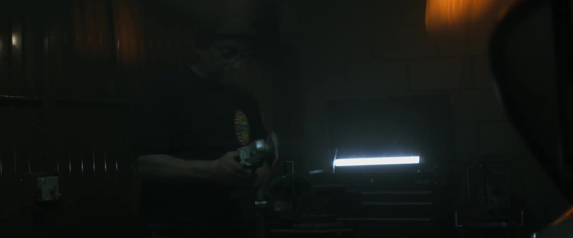 A man puts on a safety visor then saws some metal