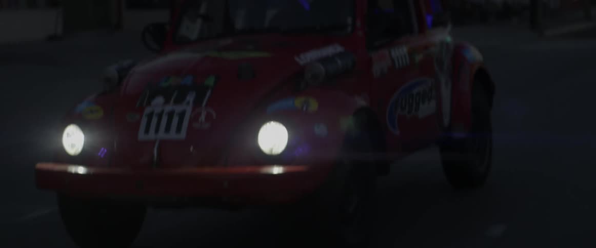A vehicle is driving down the street at night