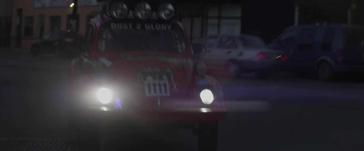 A man drives a rally car down a city road