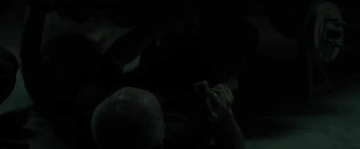 A man is working on a vehicle in the dark garage