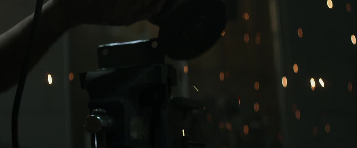 A man grinds steel with a grinding wheel