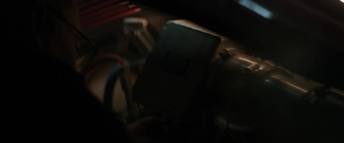 A man is repairing a machine in a dark area