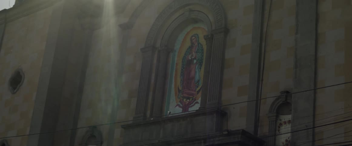 Sunlight shines over a mural of the virgin mary on a church