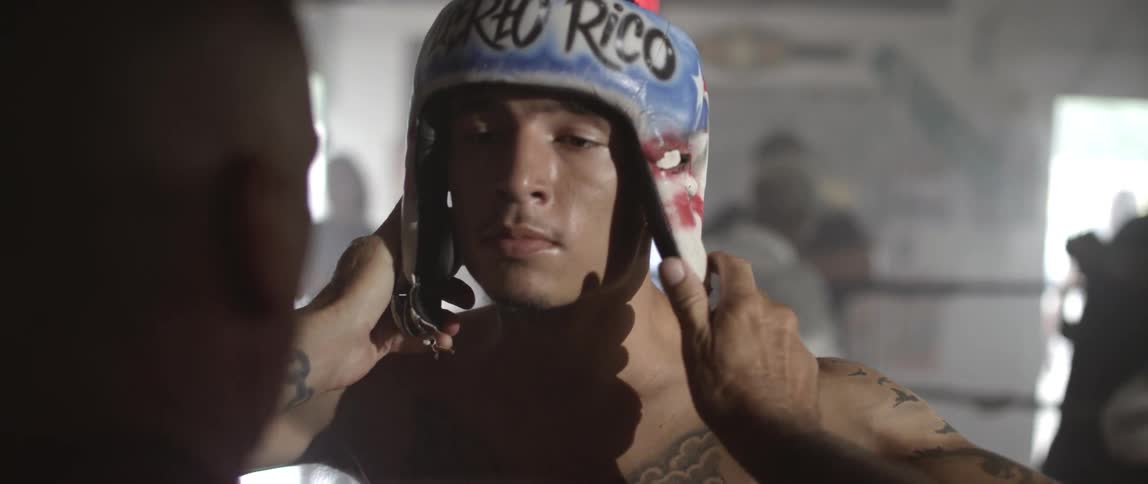 A trainer puts a boxer's helmet on