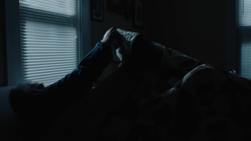 A man climbs into bed and covers himself with a blanket