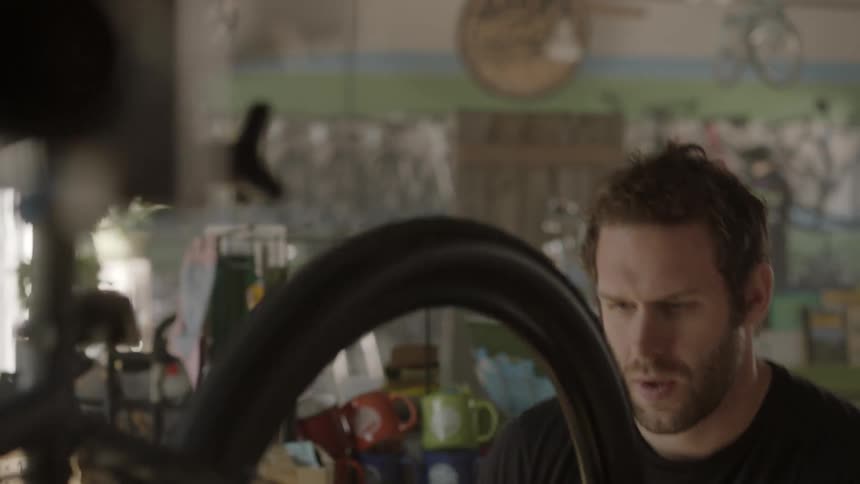 A man is working on a bicycle's wheel