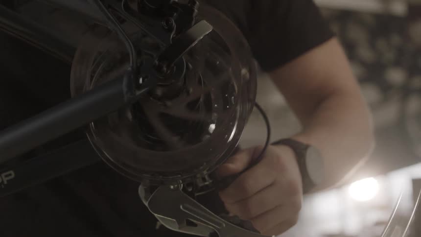 A man is working on a bicycle's gears in a bike shop