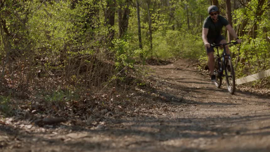 A man riding an off-road bicycle on a dirt path comes to a stop