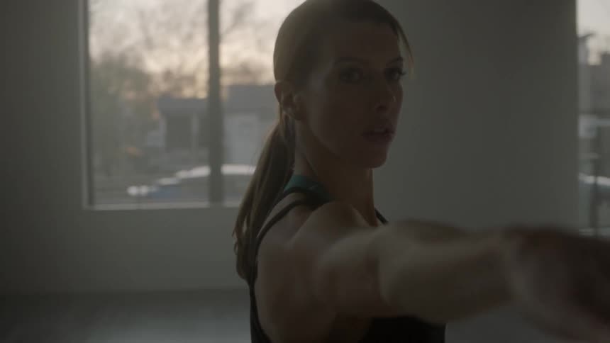 A woman holds her arm out-stretched while doing yoga