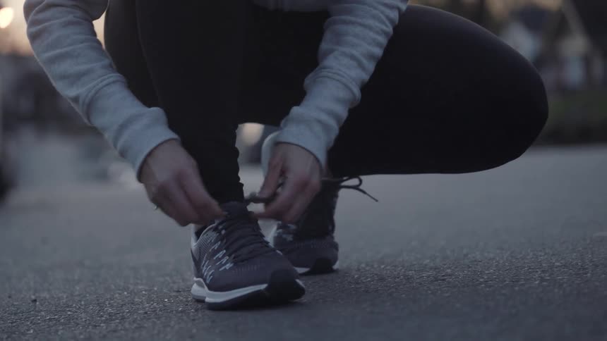 A woman bends down and ties her shoes