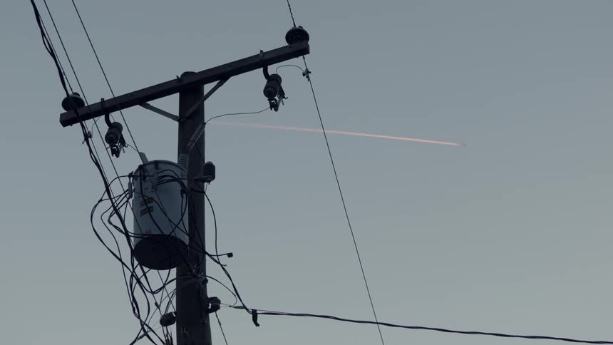 A jet flies above a power line
