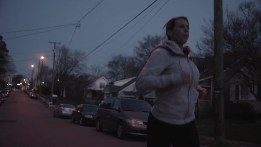 A woman jogs on a residential street at night