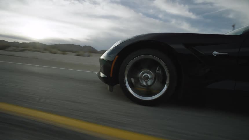A sports car speeds down a highway on a cloudy day