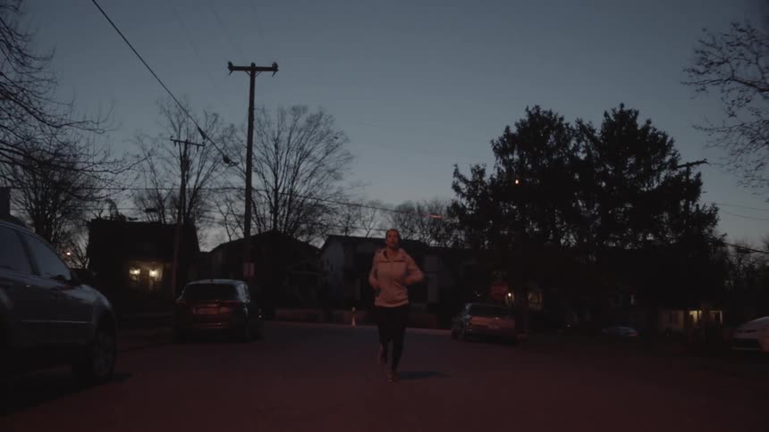 A woman jogs down a neighborhood road