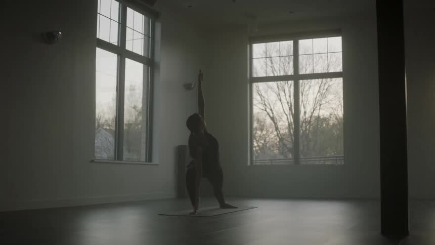 A woman is doing yoga in a room in the morning