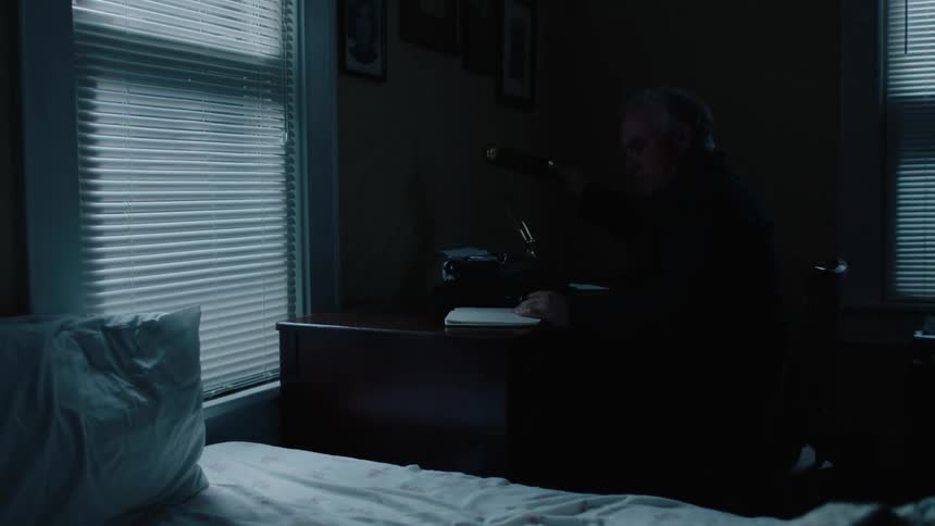 An older man gets out of bed to write something down then type it out