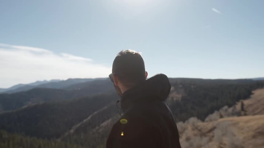 Man in a hooded jacket looks at the mountains