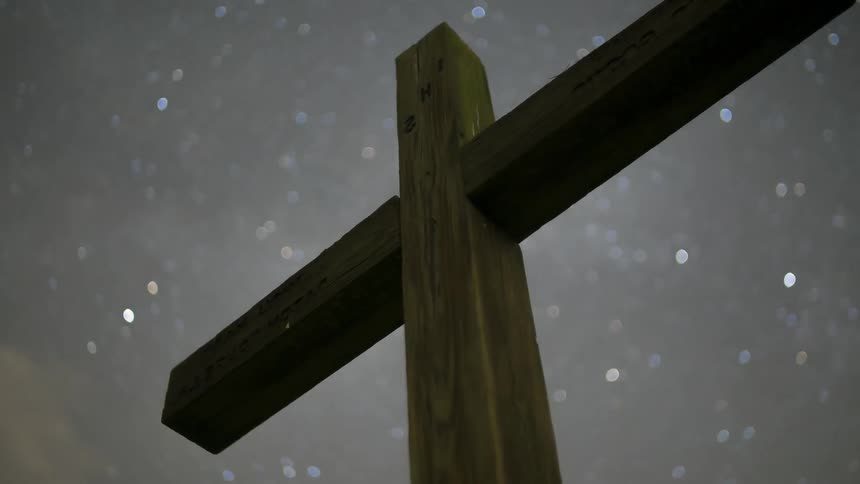 Stars spin in the sky above a wooden cross