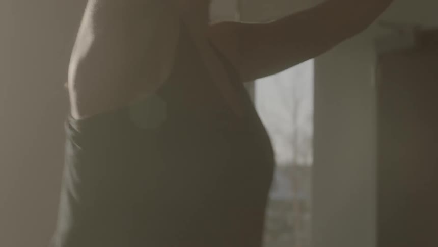 A woman does yoga in a bright room at sunrise