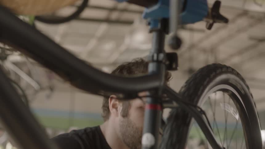 A man rotates bike tires in a bike shop