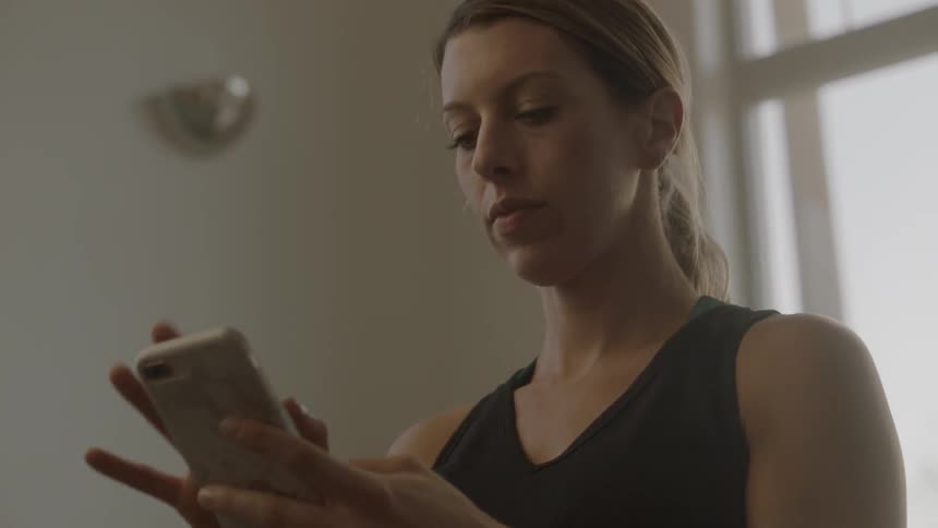 A woman is using a cell phone in a room during the day