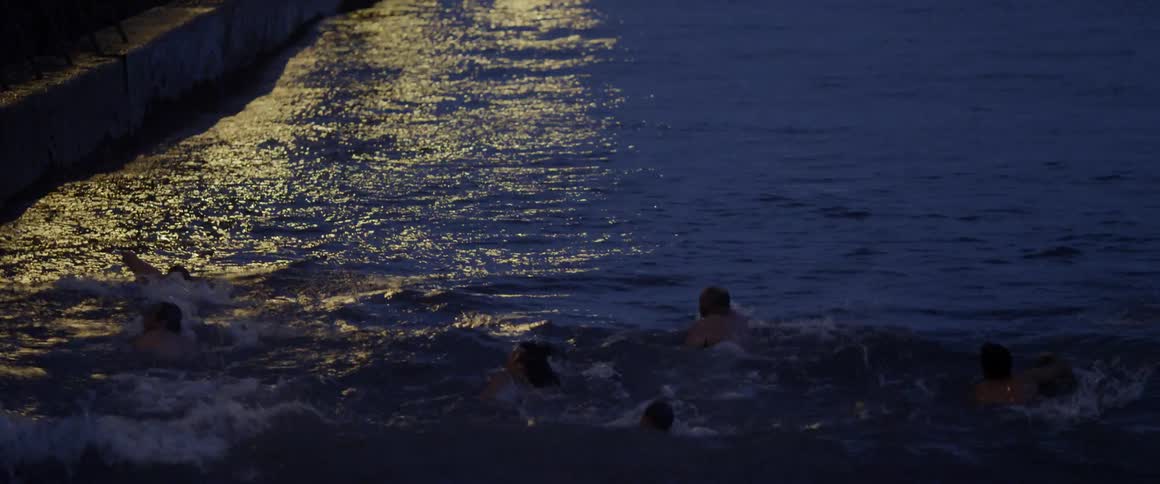 A group of swimmers swim against waves