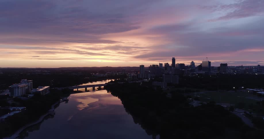 A river flowing towards a city reflects a dawn sky