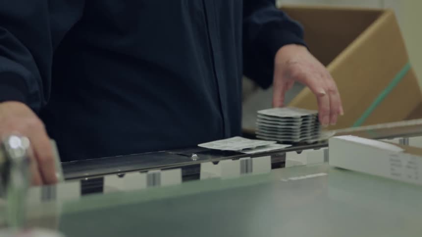 Packs of pills are placed on a moving assembly line