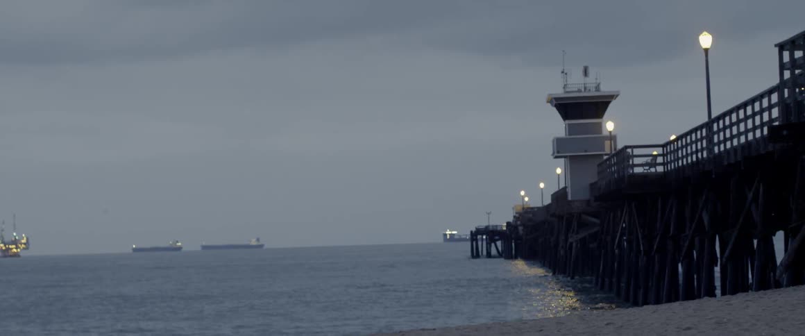 Ocean water flows around a pier at dusk