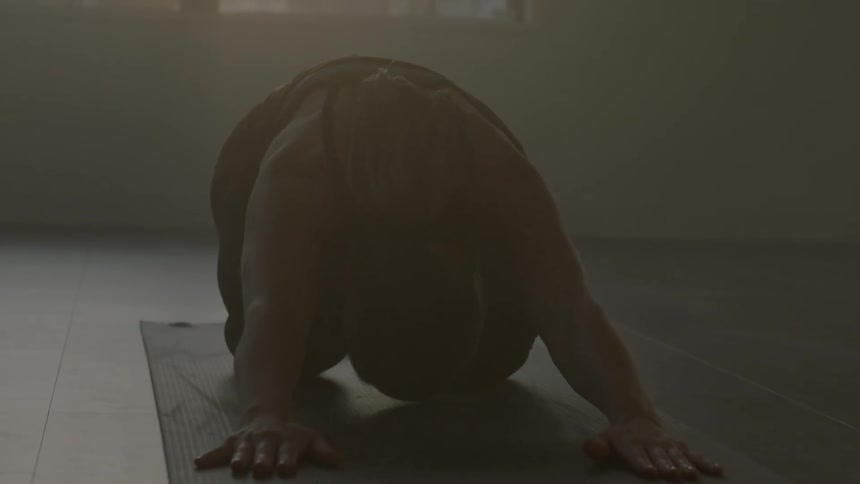 A woman stretches forward on a yoga mat