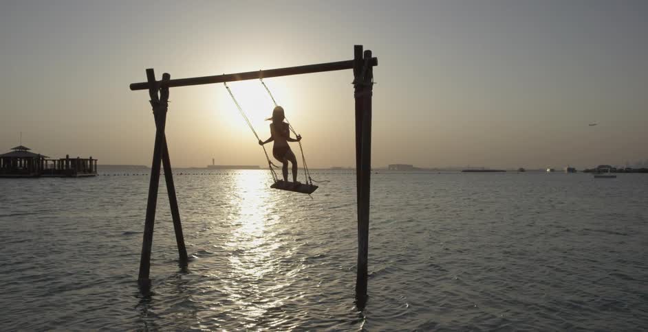 A girl swinging on a swing that is in the water