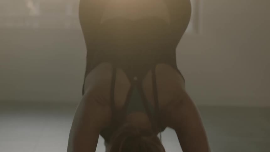 Woman stretches on a mat next to a window