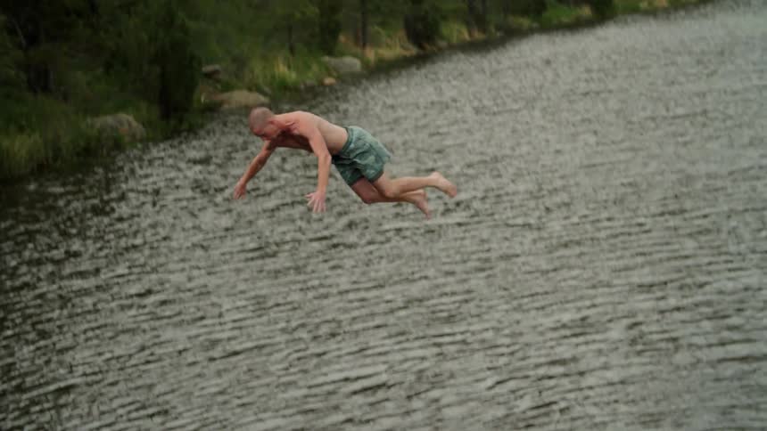 A boy dives off a rocky ledge into the water