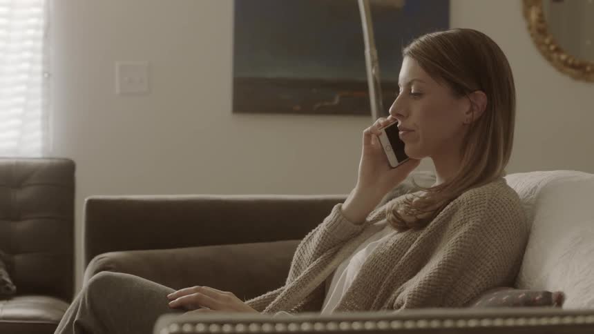 A woman talks on the phone while sitting on a couch