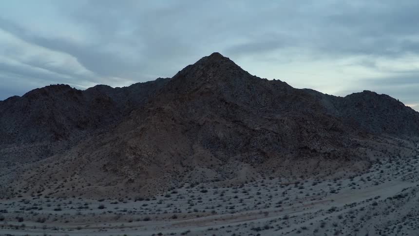 Cloud formations hang above a jagged hill line at dawn
