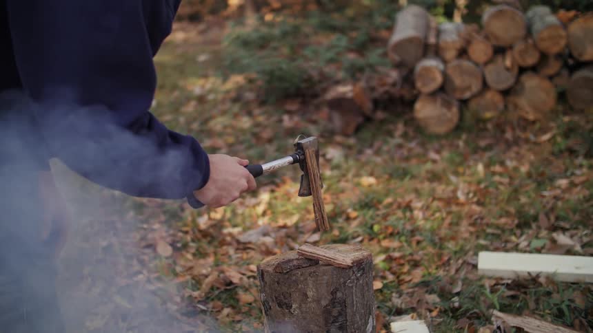 A person splits kindling with an ax